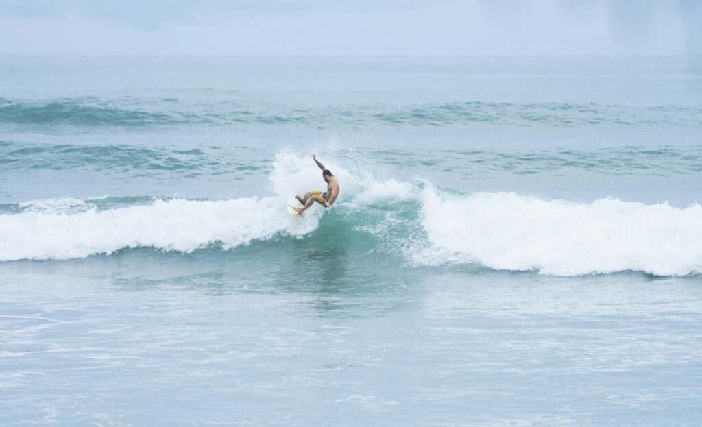 A surfer executing a powerful top turn on a wave, skillfully carving through the water with spray flying Canggu Surf