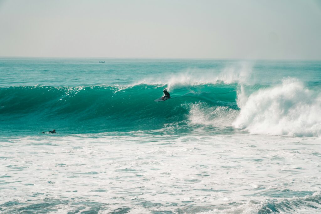 A surfer executes a massive turn on a huge blue wave at Anchor Point, Taghazout surf, Morocco