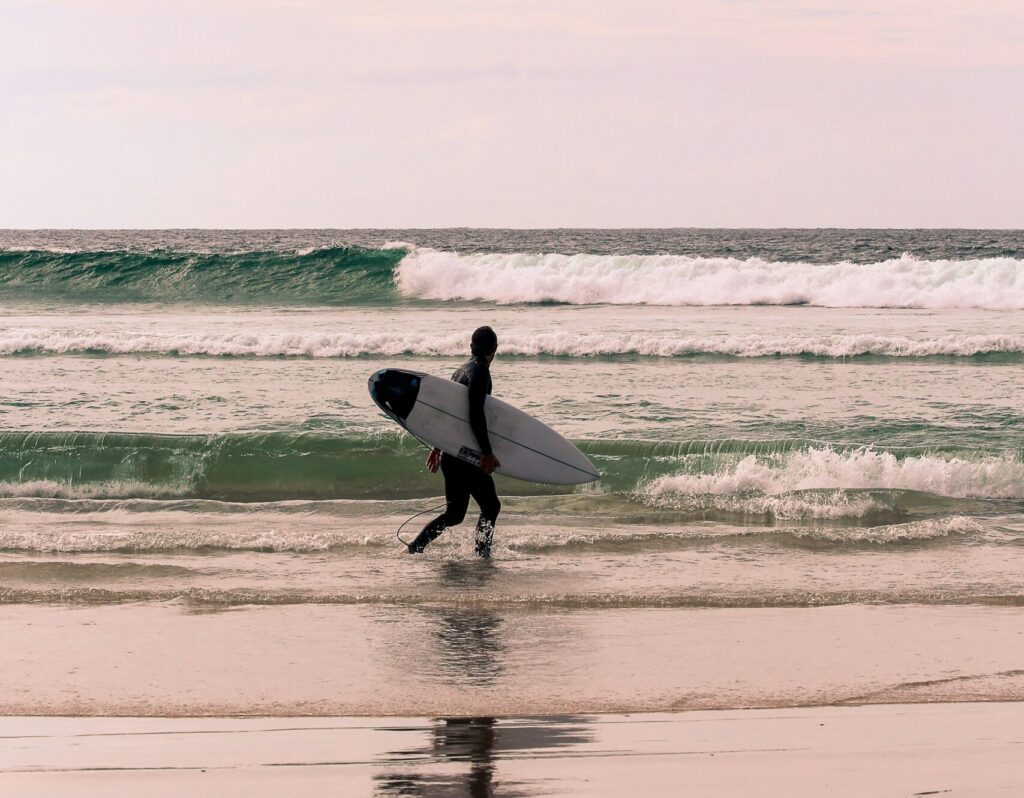 Surfer walking along the water, gazing at the waves in the background at Snapper Rocks, Coolangatta