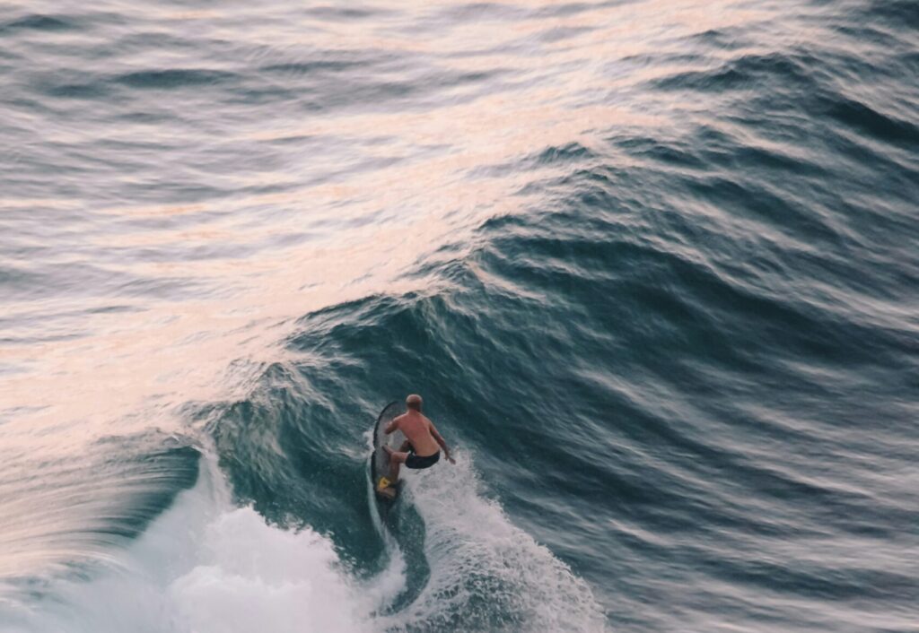 A surfer riding a long left-hand wave and performing a bottom turn, captured from above at Mompiche surf Ecuador