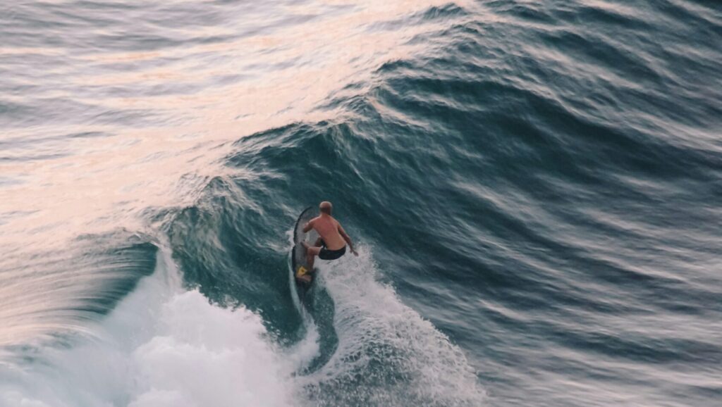 A surfer riding a long left-hand wave and performing a bottom turn, captured from above at Mompiche surf Ecuador