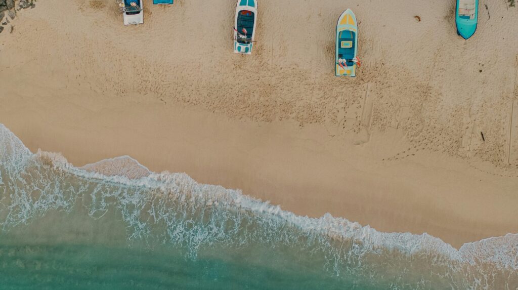 Aerial drone view of boats parked on the beach at Hikkaduwa, with gentle ocean waves rolling in