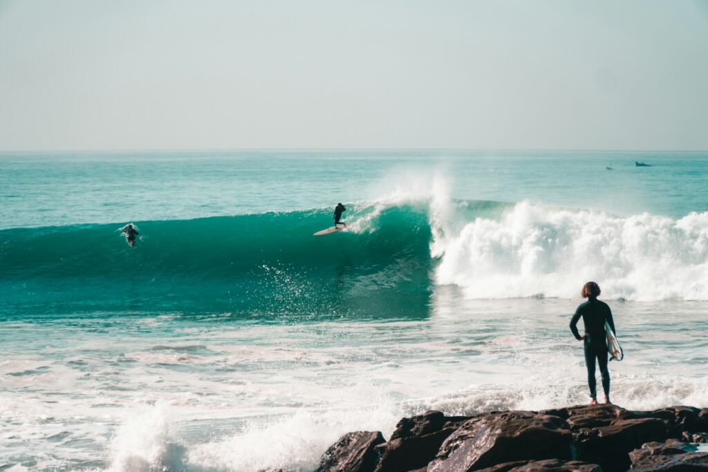 A surfer rides a massive blue wave at Anchor Point in Taghazout, Morocco surf, with a clear blue sky overhead