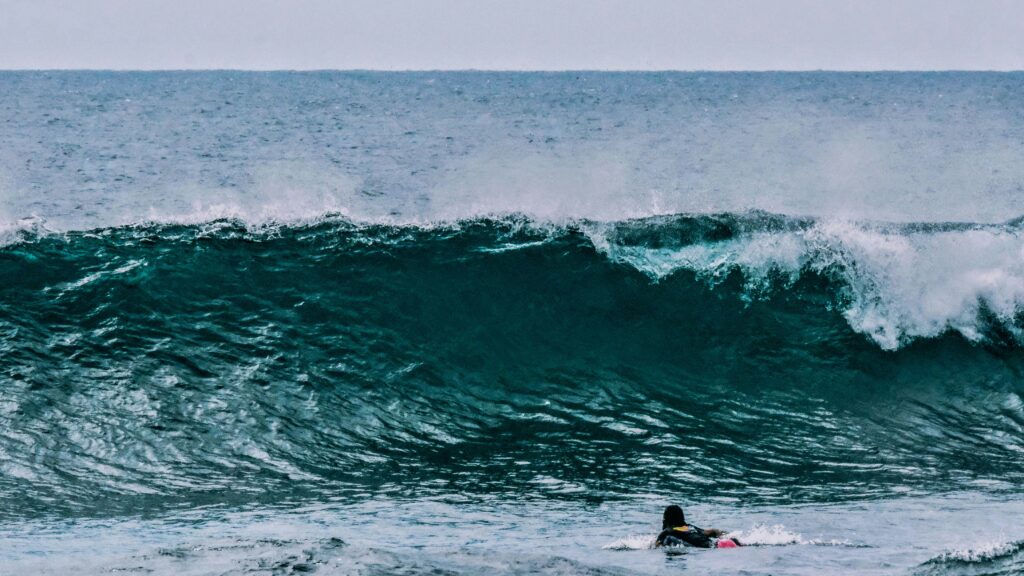 Clear blue wave with a surfer about to duck dive, set against a backdrop of clear skies in Hikkaduwa surf, Sri Lanka