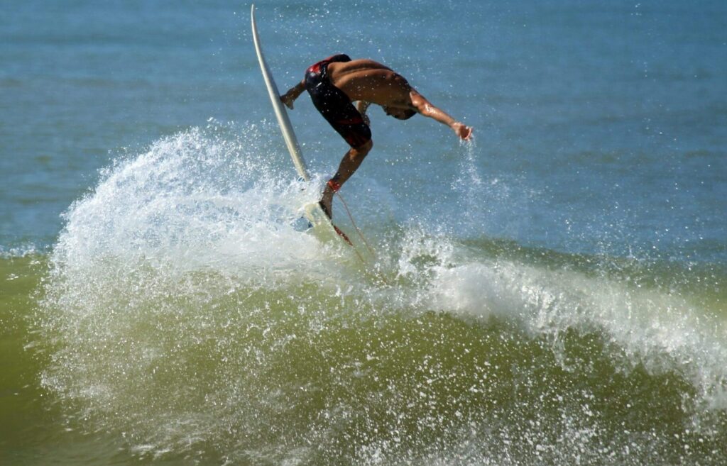 Surfer performs a frontside air over a blue-green wave at Rockaway Beach surf, Queens, NY