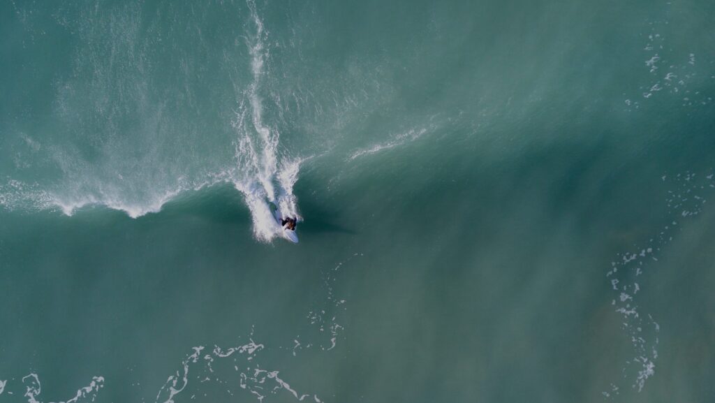 A bird's-eye view of a surfer just taking off on a left-hand wave, captured mid-action in Mompiche surf, ecuador