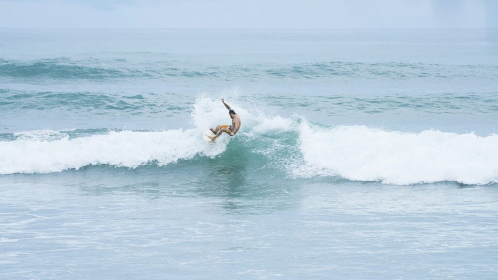 A surfer executing a powerful top turn on a wave, skillfully carving through the water with spray flying in Playa las flores surf