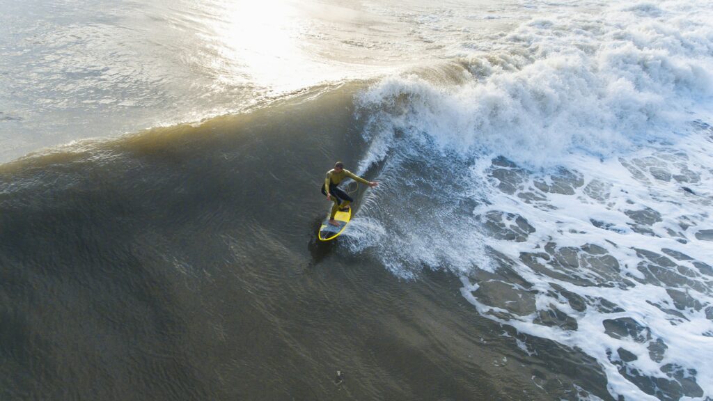 Surfer riding a left-hand wave, skillfully maneuvering along the face with a bright yellow surfboard at Sunshine Coast