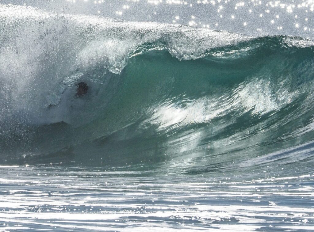 Surfer in a left-hand barrel at Moffat Beach, Caloundra, with vibrant blue water and clear skies