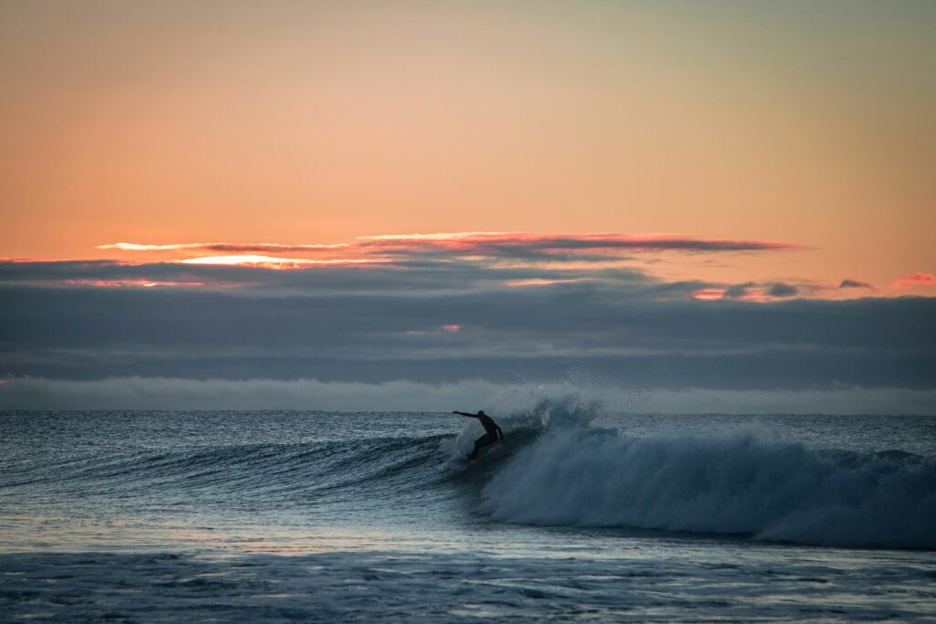 Surfer doing a front-side turn at Bells Beach Surf, Torquay, during sunrise with vibrant yellow skies