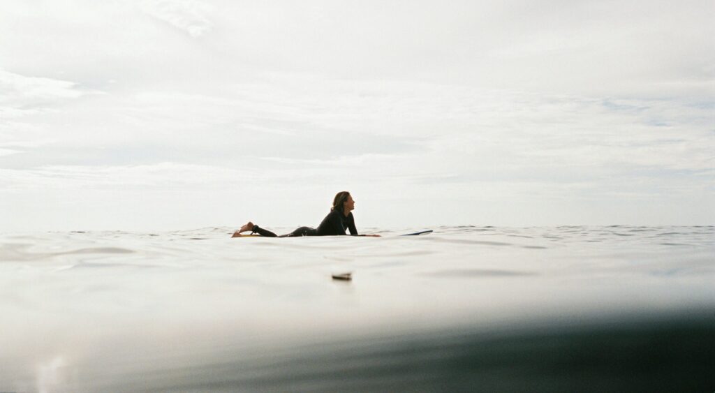 A girl relaxing on a surfboard in calm water, surrounded by cloudy skies, Arugam Bay surf