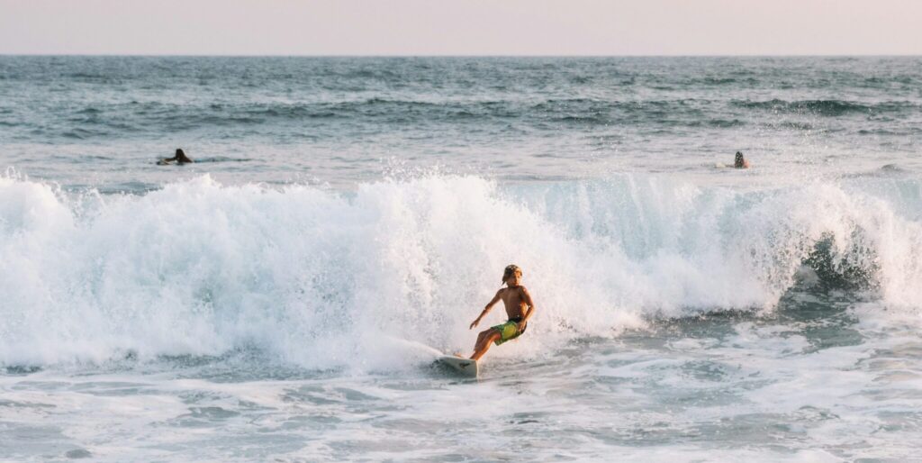 A kid surfer just finishing a ride as the wave closes out in el Tunco surf, with the ocean in the background and water crashing down