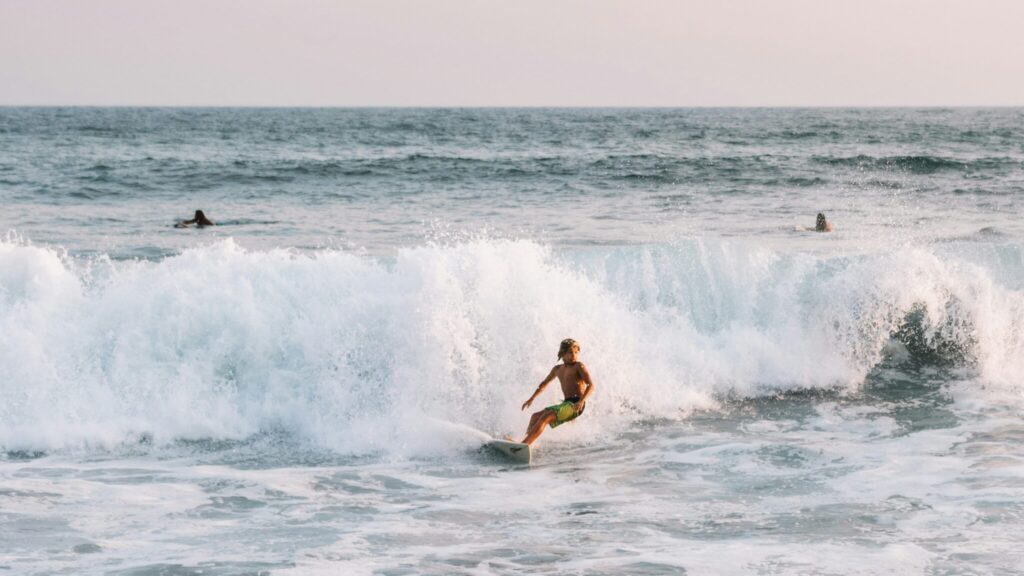 A kid surfer just finishing a ride as the wave closes out in el Tunco surf, with the ocean in the background and water crashing down