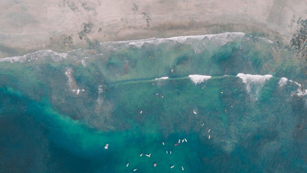A bird's-eye view of Tamarindo Surf Beach, Costa Rica, showing surfers sitting in ocean.