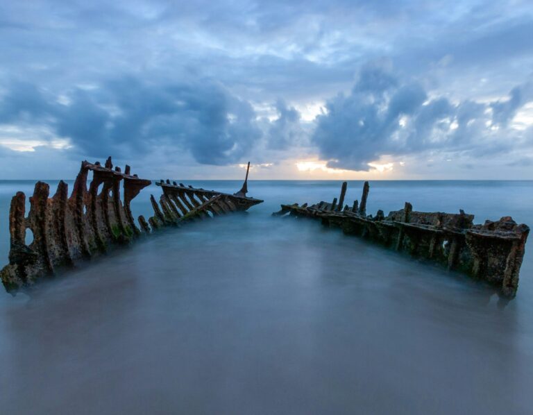 Ocean view of the SS Dicky Shipwreck in Caloundra during sunrise, with warm light reflecting off the water