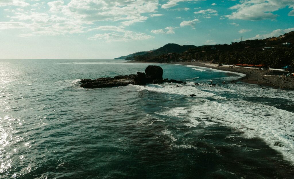 A drone photo of El Tunco surf, El Salvador, showcasing the ocean and beach, with surrounding hills