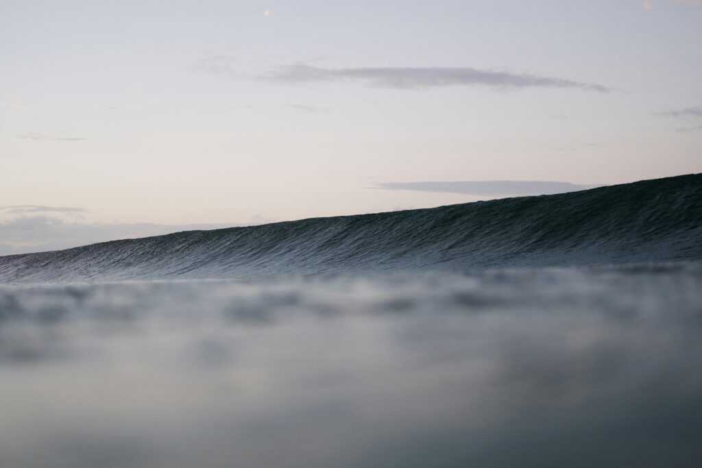 Rolling dark wave at The Pass, Byron Bay, captured from the water with grey skies overhead