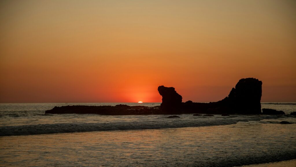 El Salvador Surf Guide 2025 | The Best Surf Towns With Easy Access A vibrant sunset at El Tunco surf, El Salvador surf, with orange and yellow skies over the ocean.