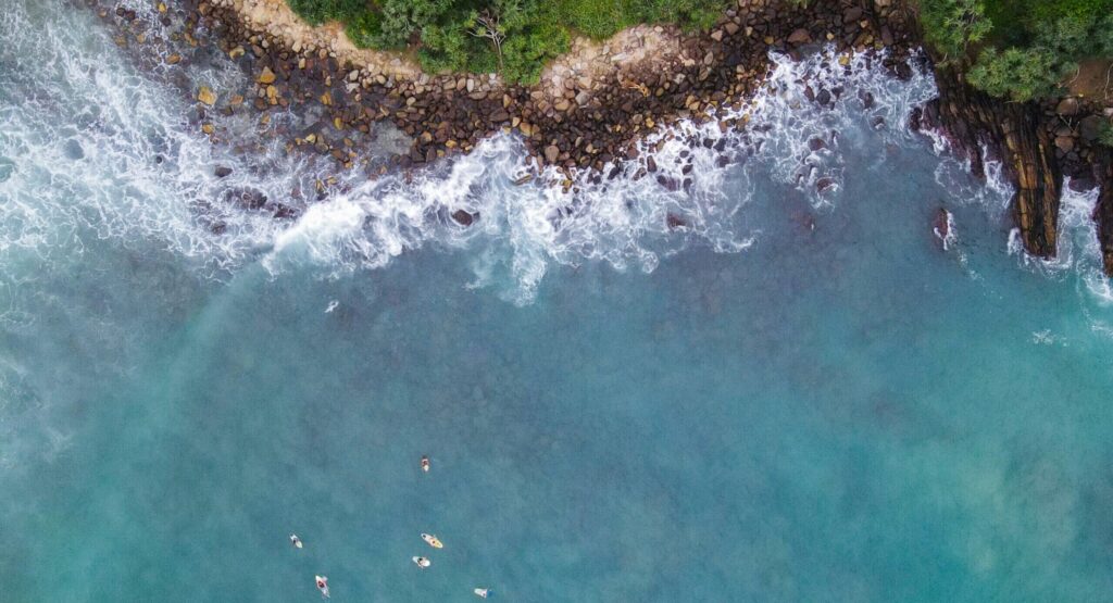 Bird's eye drone view of surfers in the water at Hiriketiya Surf Beach, waiting for waves