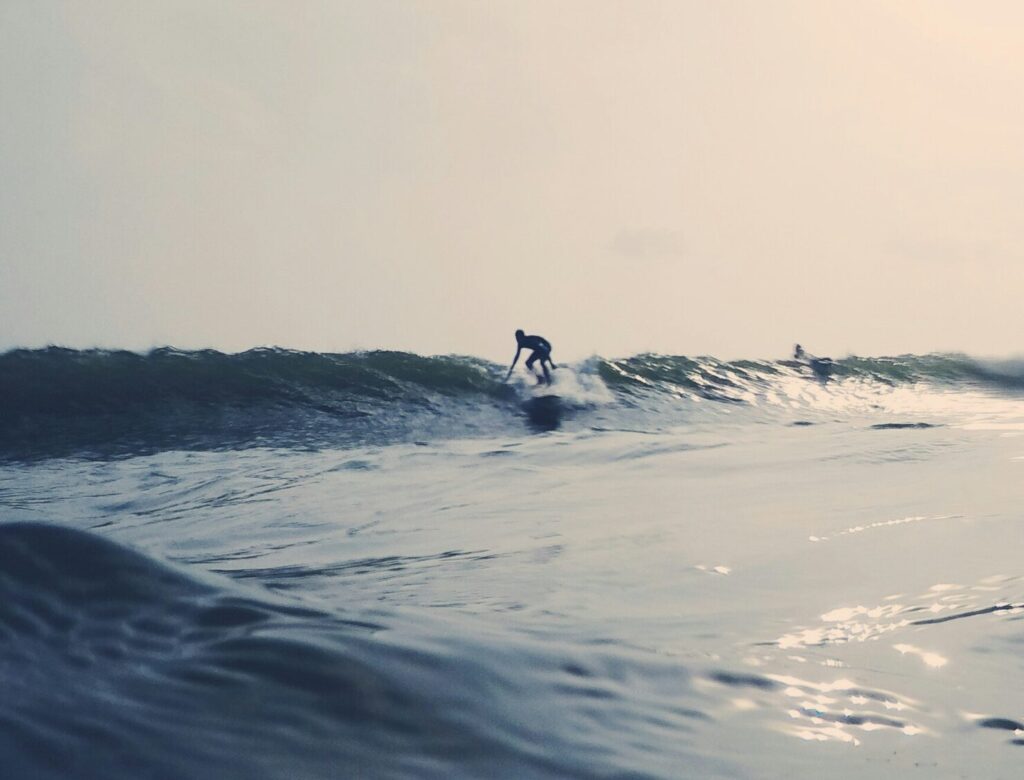 Surfer taking off on a right-hand wave riding a malibu surfboard at Weligama Surf Beach, Sri Lanka