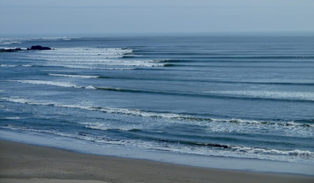 The long left-hand waves of Chicama surf in Peru, rolling endlessly under clear skies, with wave after wave peeling perfectly