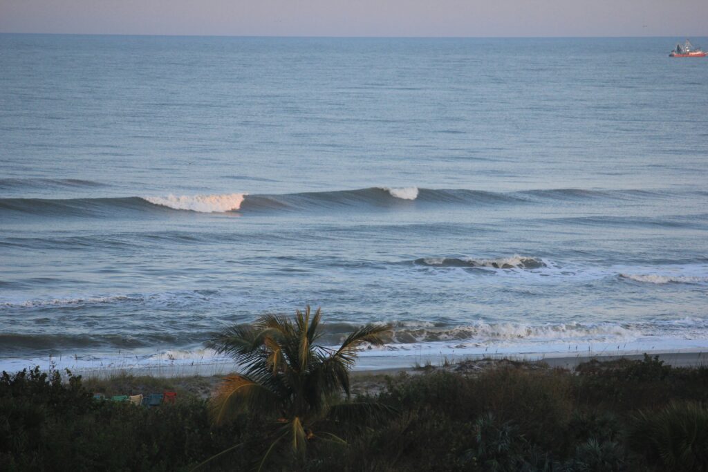 A wave breaking at Cocoa Beach surf, Florida, showcasing the vibrant blue ocean and the dynamic movement of water