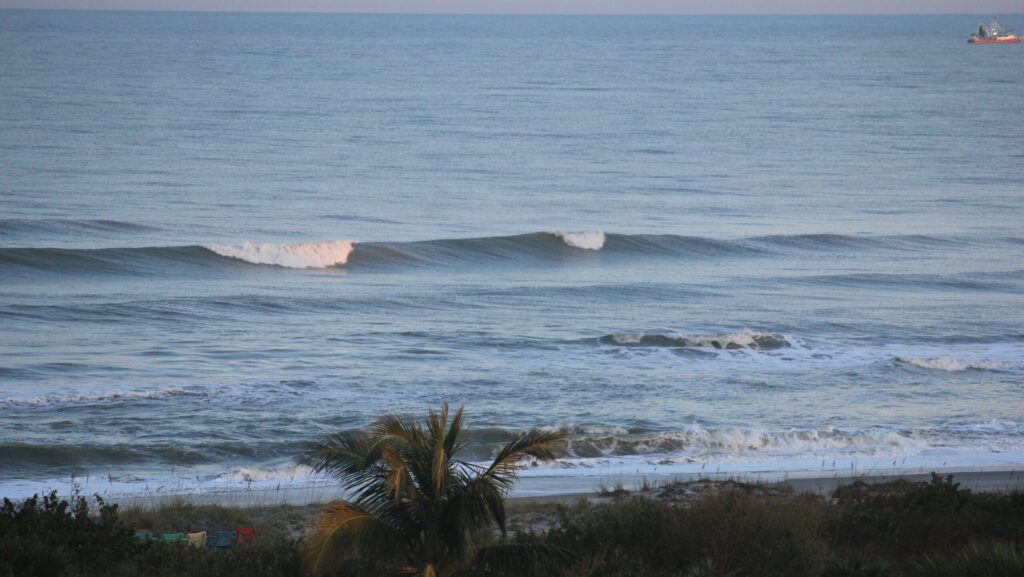 A wave breaking at Cocoa Beach surf, Florida, showcasing the vibrant blue ocean and the dynamic movement of water