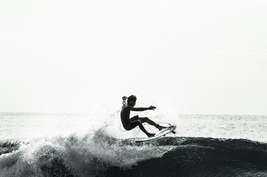 Black and white image of a surfer executing a floater maneuver atop a broken wave, skillfully riding along the wave’s edge in Cadiz Surf, Spain