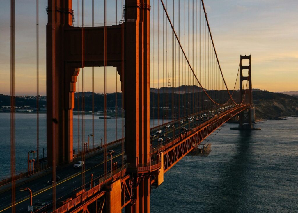 The Golden Gate Bridge glows in the warm light of sunset, framed by clear skies, as the sun casts a golden hue over the iconic structure in San Francisco, California