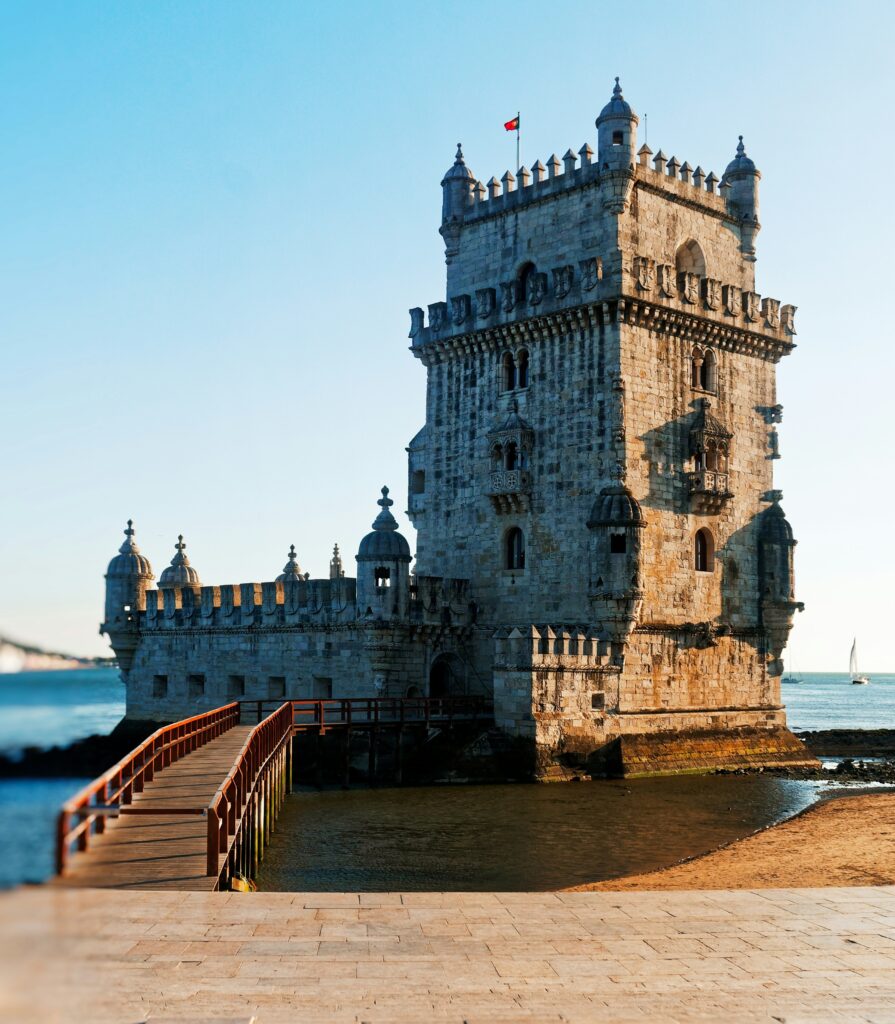 Belém Tower in Lisbon at low tide, showcasing its majestic structure against clear blue skies