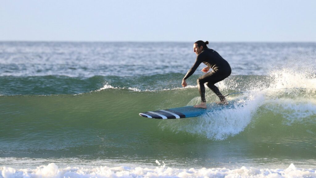 A surfer rides a waist-high wave on a longboard at Narragansett surf, Rhode Island, gliding smoothly on a right-hand point break under clear, sunny skies