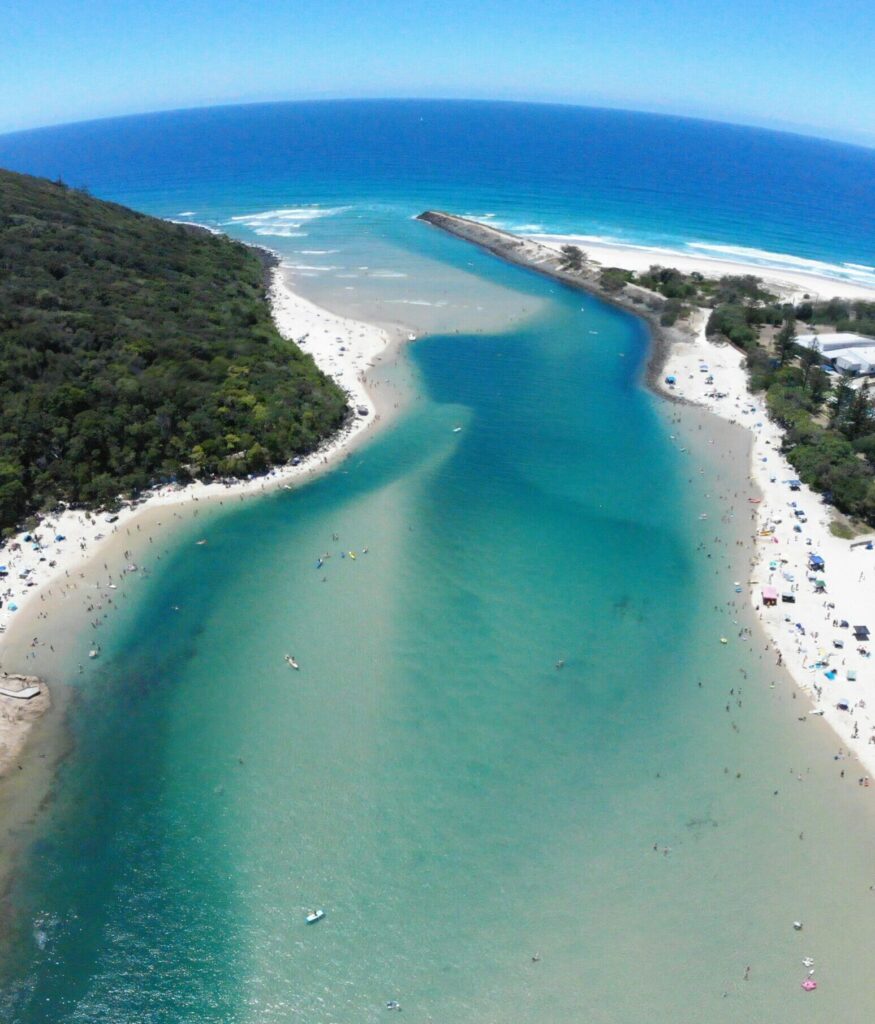 Aerial view of Tallebudgera Creek at Burleigh Heads, showcasing the ocean and clear blue skies