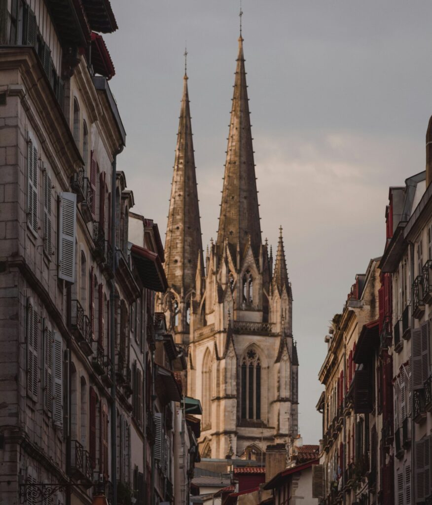 Apartment buildings frame a distant view of the Bayonne Cathedral, highlighting its stunning architecture in the center of the scene