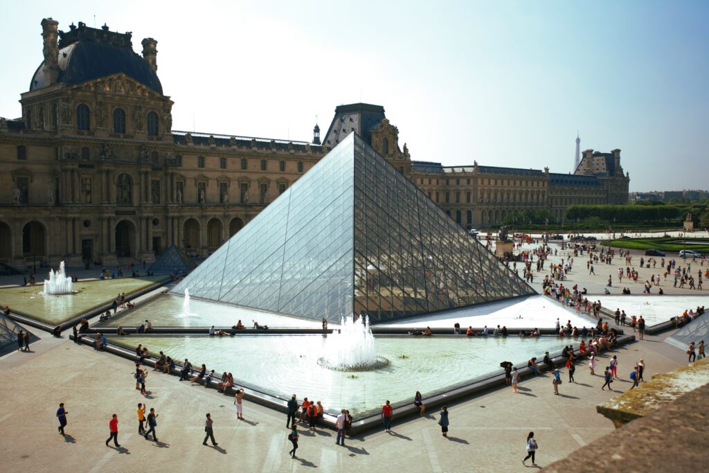 The Louvre Museum in Paris, France, featuring the iconic glass pyramid and its striking angles, beautifully framed against the historic architecture