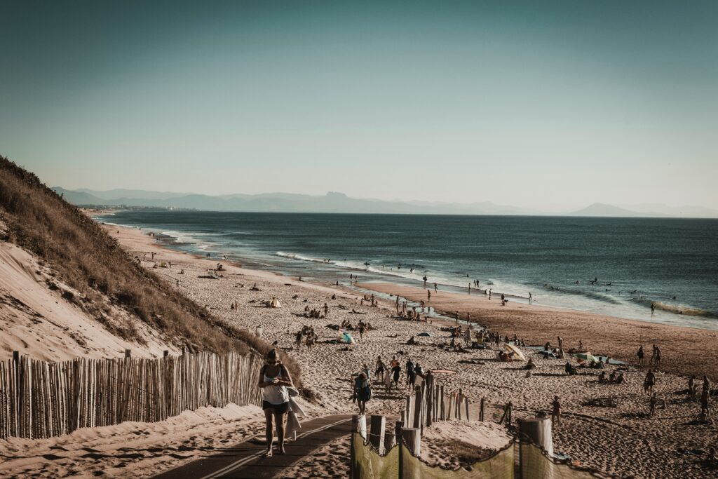 The ocean in Capreton surf, France, showcases a long stretch of sandy beach with people enjoying the sun and surf along the shoreline