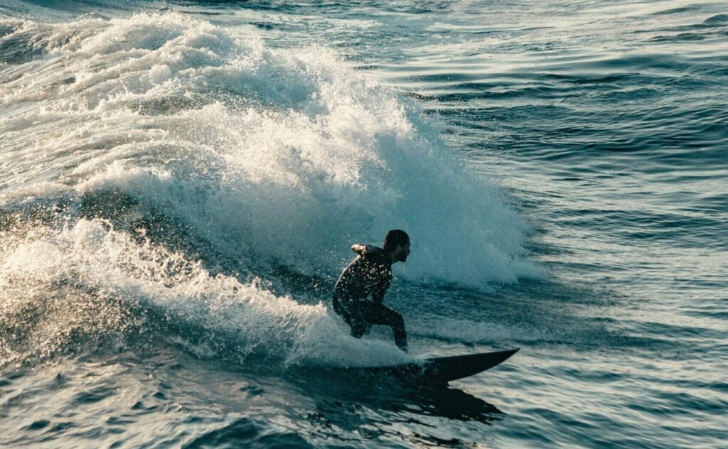 surfer performs a big cut back turn with lots of spray with blue water, surfing at Huntington Beach Surf Pier, California