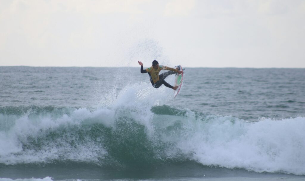 Surfer launching into a huge air at Supertubos, Peniche Surf, Portugal, with clear skies and vibrant blue water