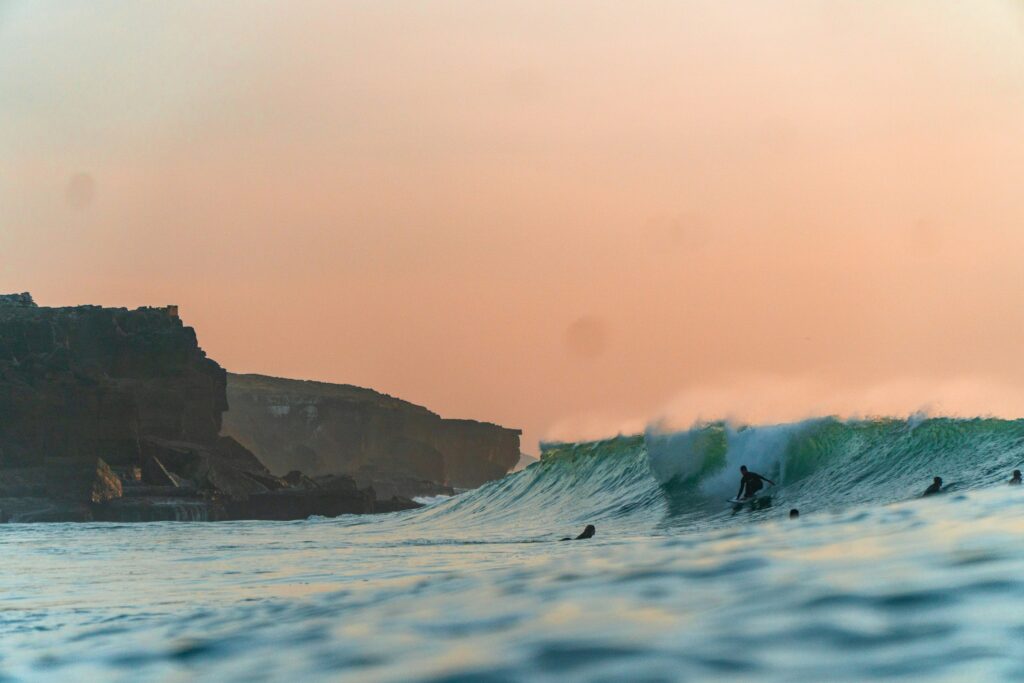 Surfer tucking into a barrel under clear yellow skies, captured from the ocean at Ribeira d'Ilhas - Ericeira surf