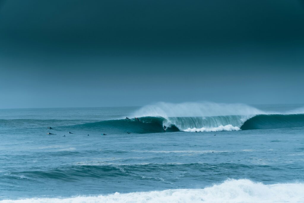 A surfer caught in a barrel of a massive wave at Plage de la Gravière in Hossegor surf, with dark skies