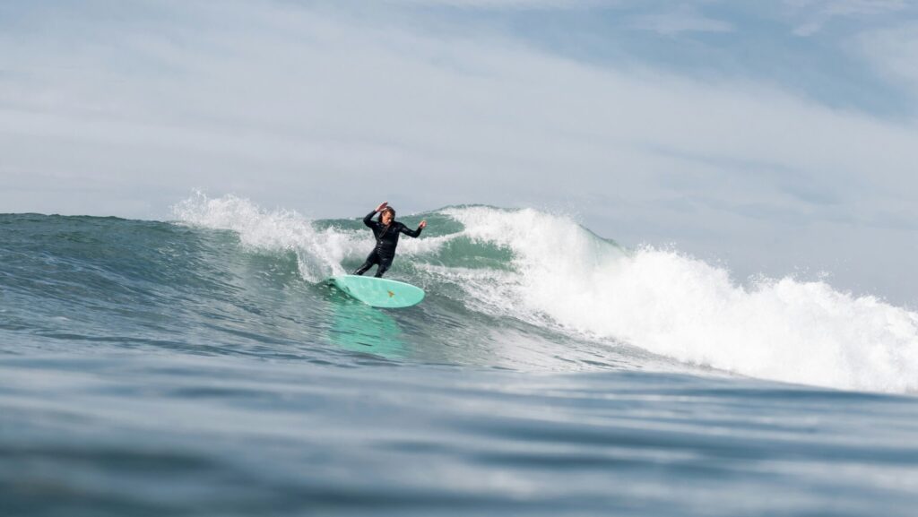 Surfer doing a cutback on a wave under blue skies at Sunset Cliffs Surf, CA, captured from the water