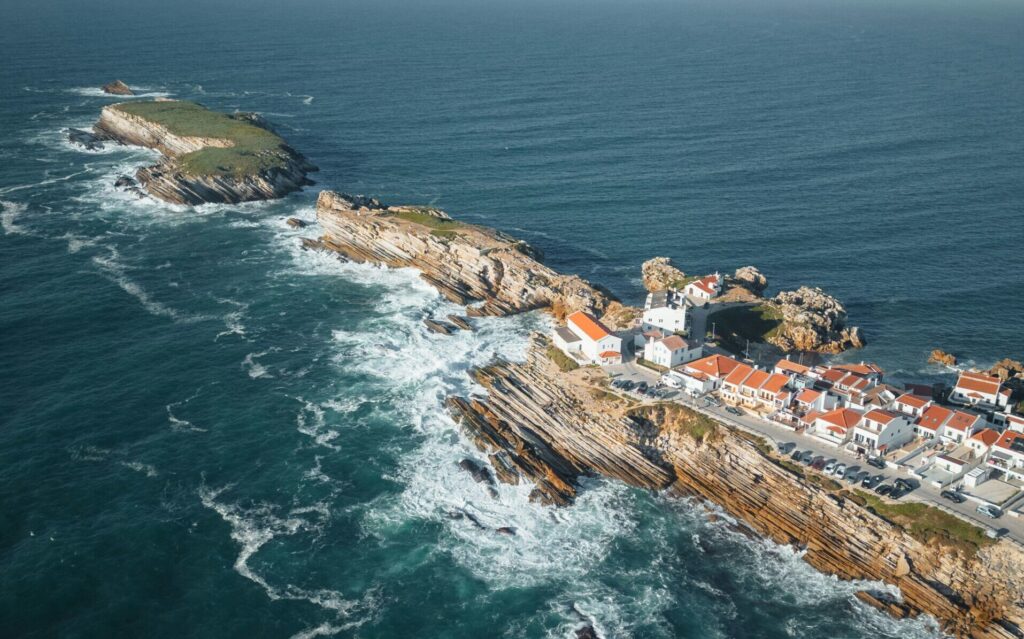 Drone view of Peniche, Portugal, showcasing the town surrounded by the ocean and dramatic cliffs