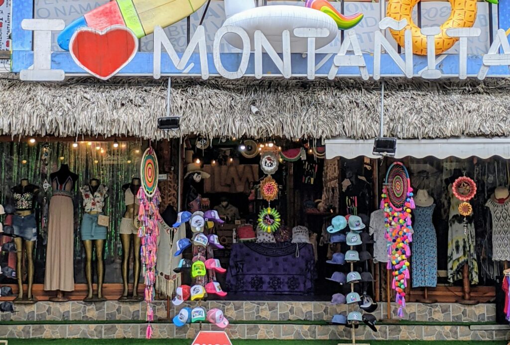 A shop in Montañita, Ecuador, showcasing hats and clothes, with a large sign that reads "I Love Montañita" prominently displayed in front