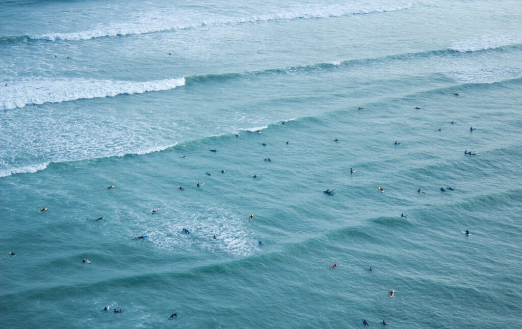 Many people surfing at Waikiki Beach, Miraflores surf, Lima, riding rolling waves in a vibrant blue ocean, capturing the lively beach atmosphere