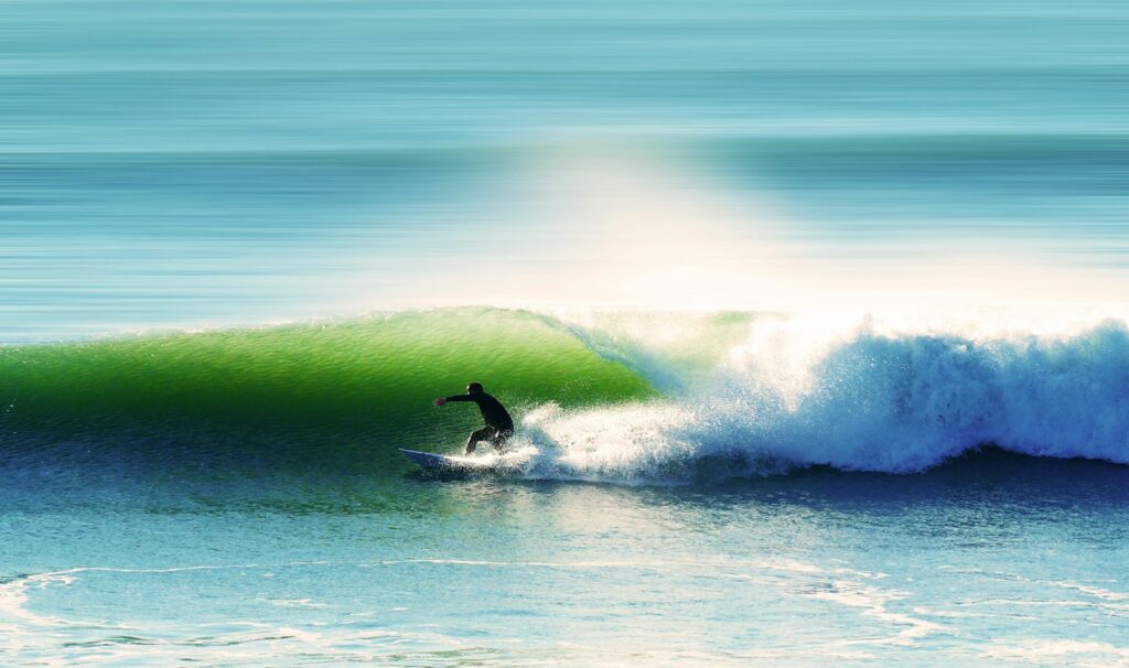 A surfer executes a bottom turn on a green-blue right-hand wave in Les Sables-d'Olonne Surf, France