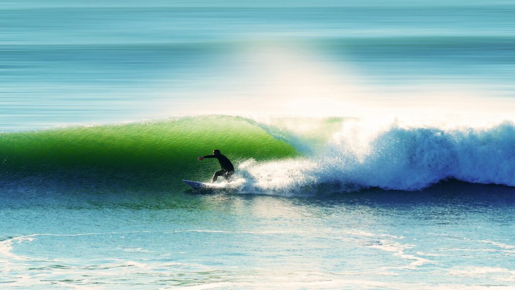 A surfer executes a bottom turn on a green-blue right-hand wave in Les Sables-d'Olonne Surf, France