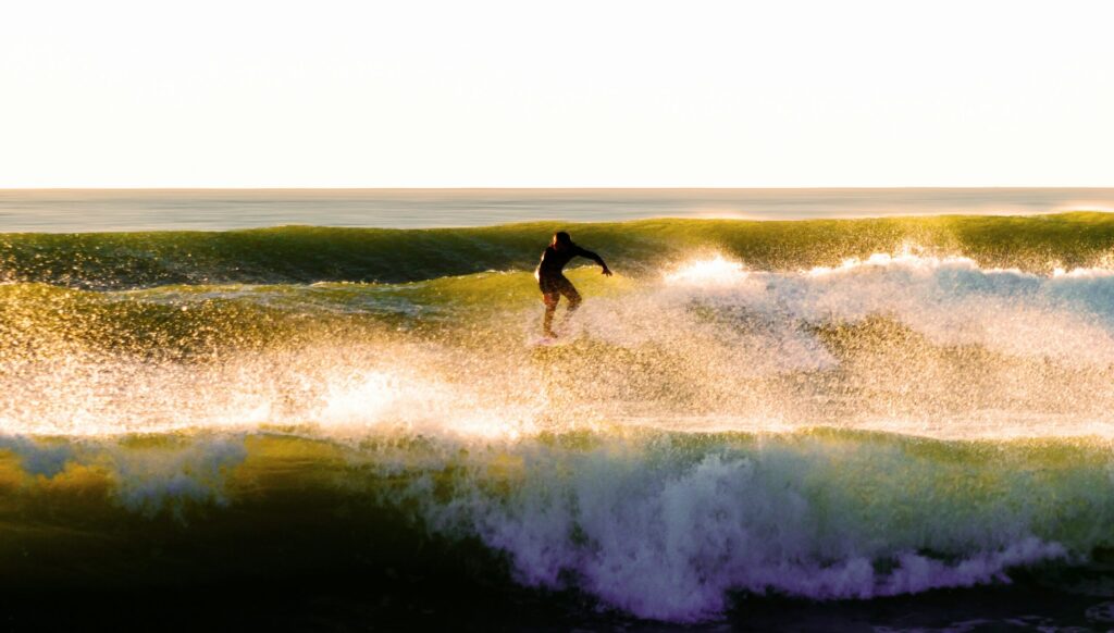 A surfer rides a wave at Les Sables-d'Olonne surf, surrounded by rolling waves in both the foreground and background