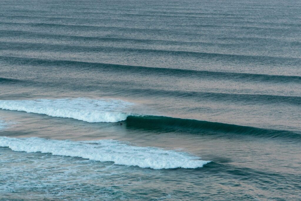 Rolling left-hand waves under pink and blue skies at Ribeira d'Ilhas - Ericeira surf