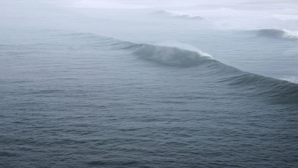 Waves seen from behind in Anglet surf, France, under a grey and cloudy sky, creating a moody and atmospheric coastal scene