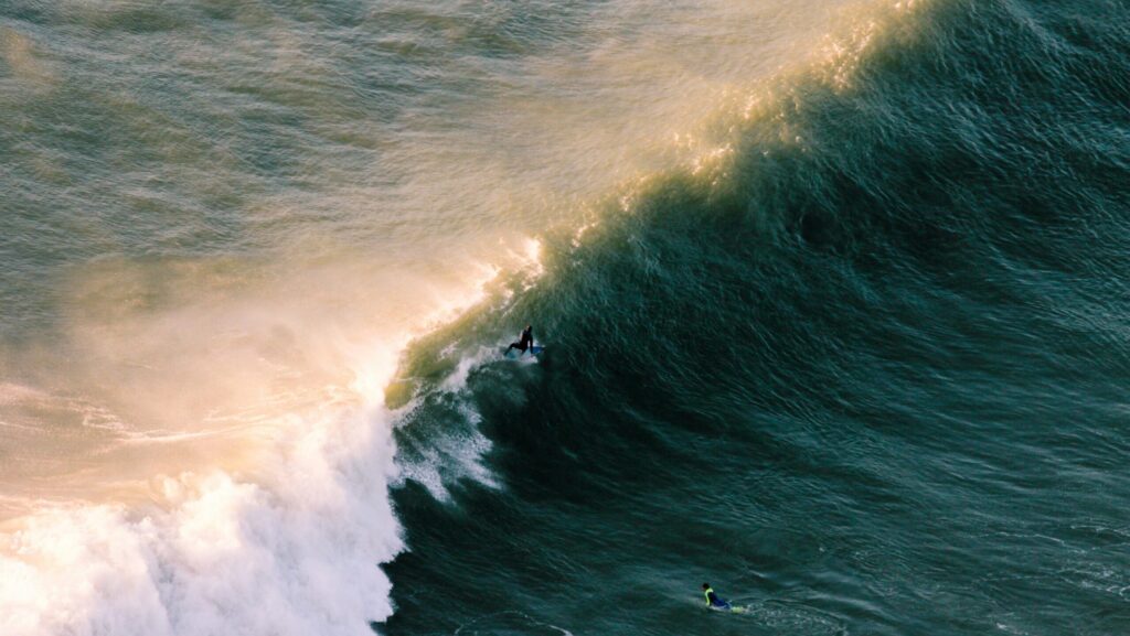 A large left-hand wave at Lobitos Surf Point, Lobitos, Peru, with a man surfing, captured from above, highlighting the vibrant ocean scene