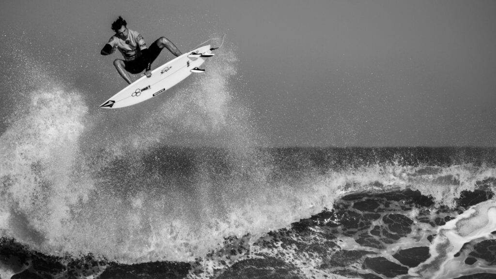 A surfer executing a huge aerial maneuver above the wave in Lacanau Surf, France, showcasing skill and style